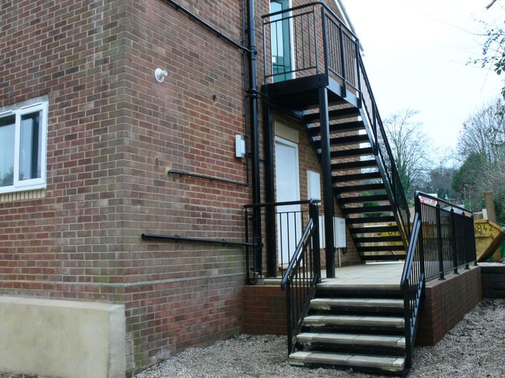 a brick building with stairs leading up to the front door and second story balcony area