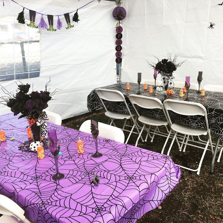 the table is set up with purple cloths and black spiderweave decorations on it