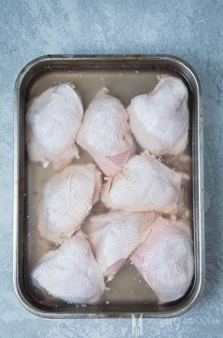 raw chicken in a metal pan with water