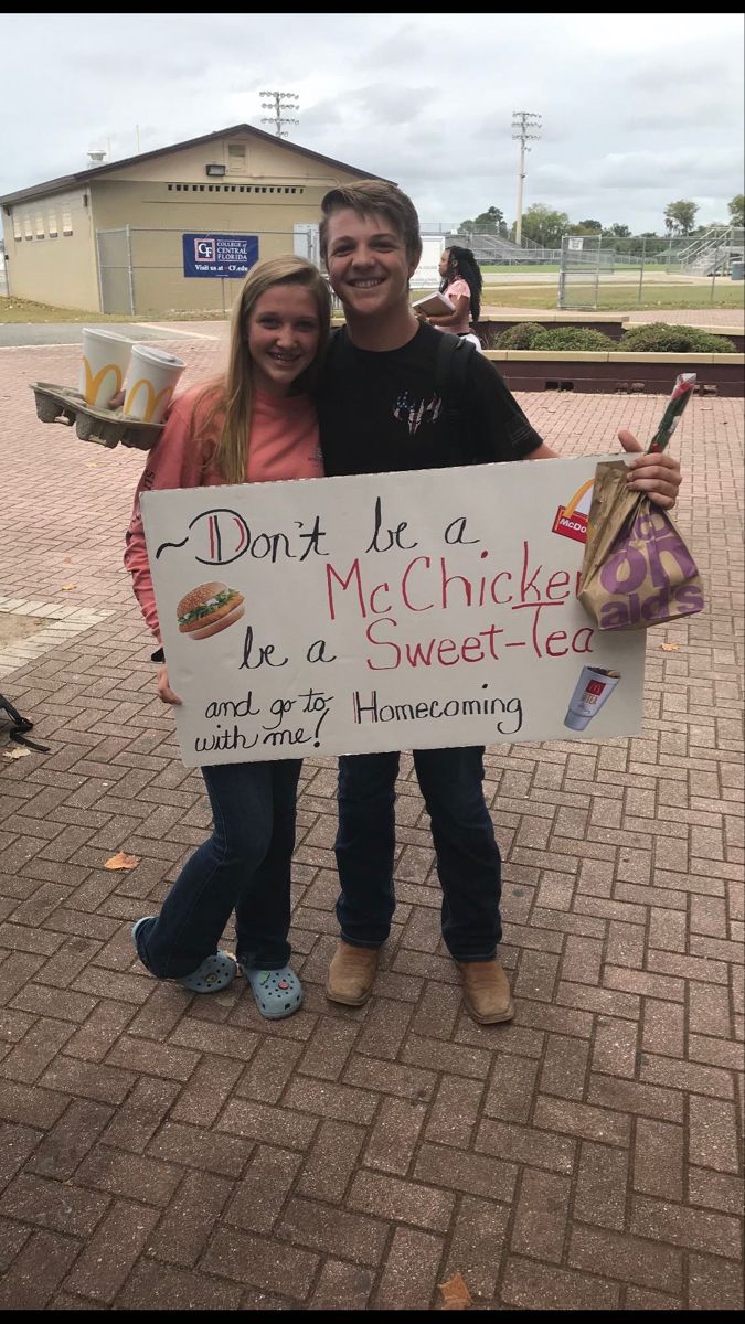 a man and woman standing next to each other holding a sign