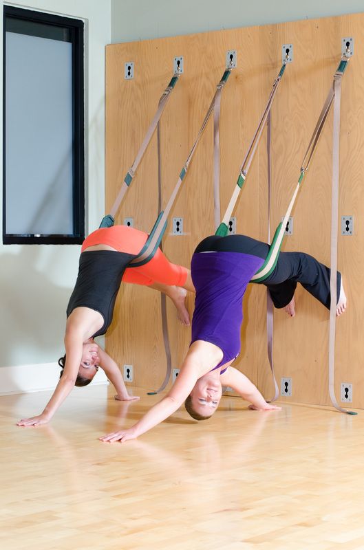 two people doing handstands on the floor in front of a wall with arrows