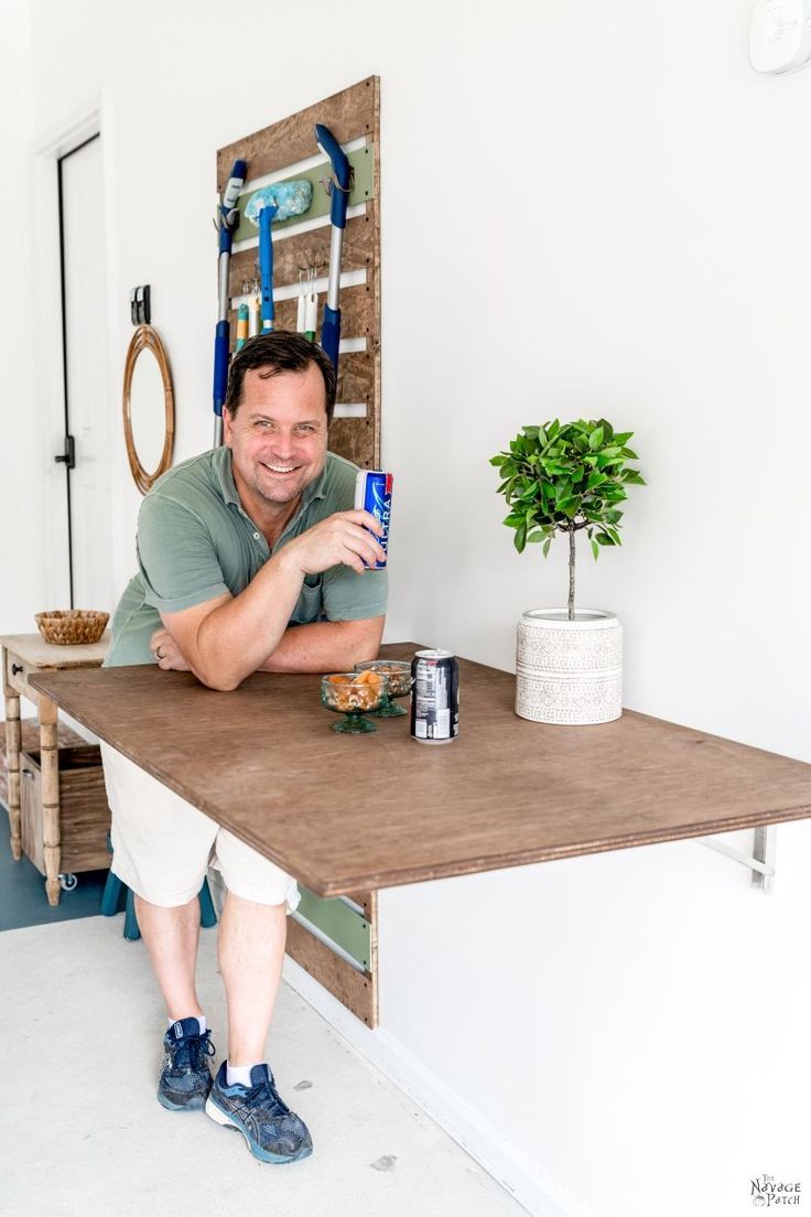 a man sitting at a table with his hand on the top of it and smiling