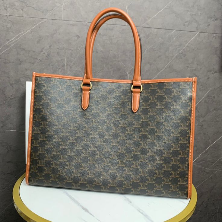 a brown and black purse sitting on top of a white table next to a wall