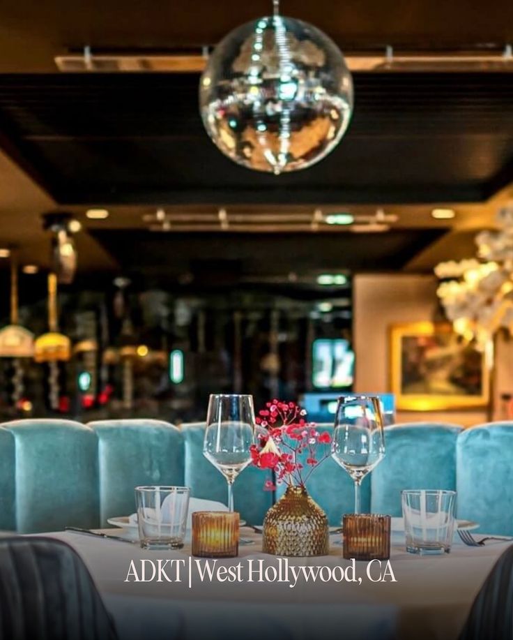 a restaurant with blue booths and chandelier hanging from the ceiling, filled with wine glasses