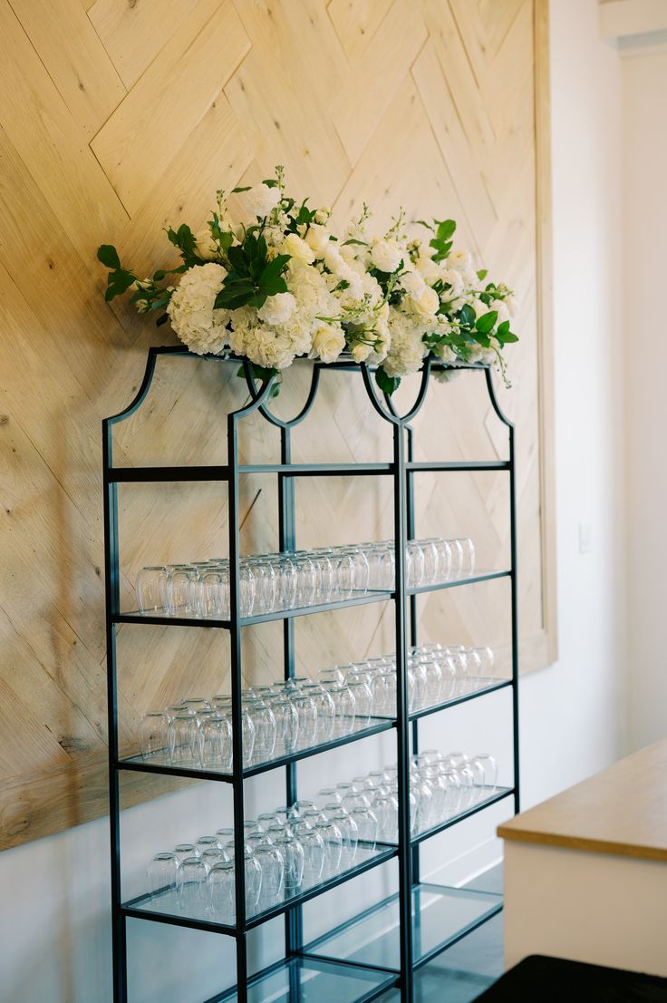 a display case with flowers and wine glasses