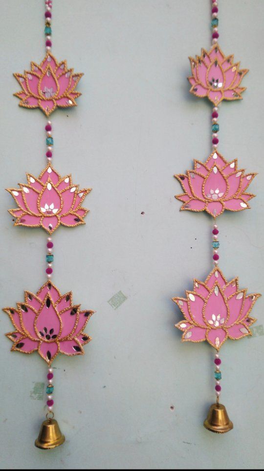 pink and gold necklace with bells hanging from it's sides on a white surface