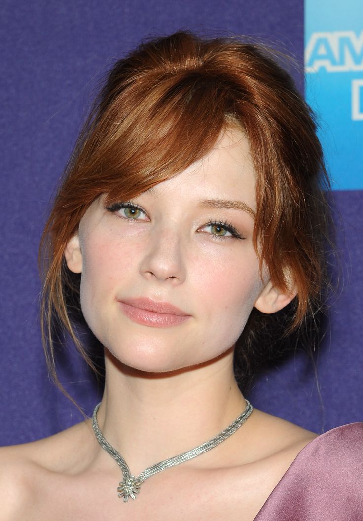 a close up of a person wearing a necklace and dress with hair in the wind