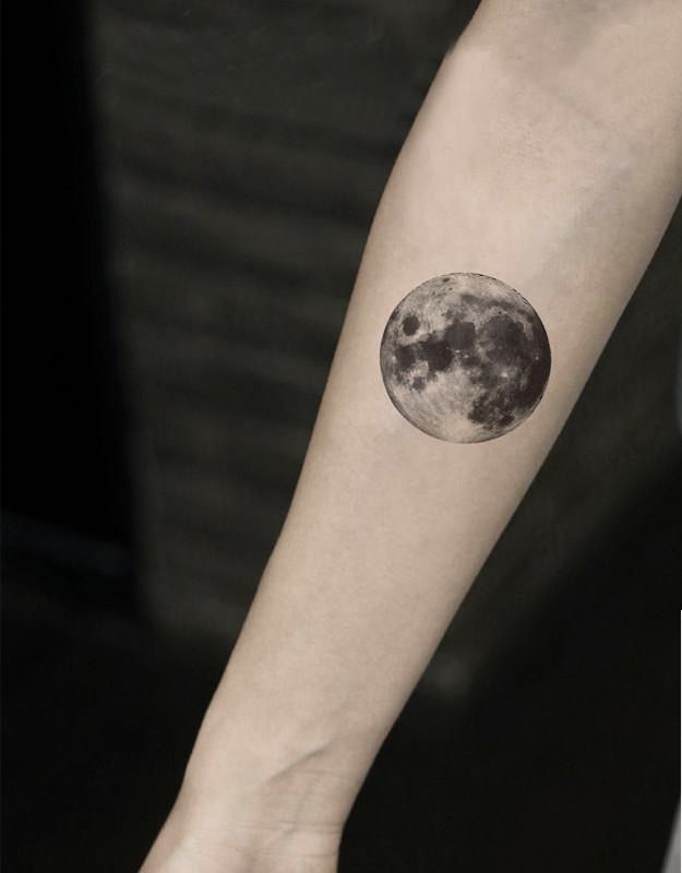 a woman's arm with a small tattoo of the moon and stars on it