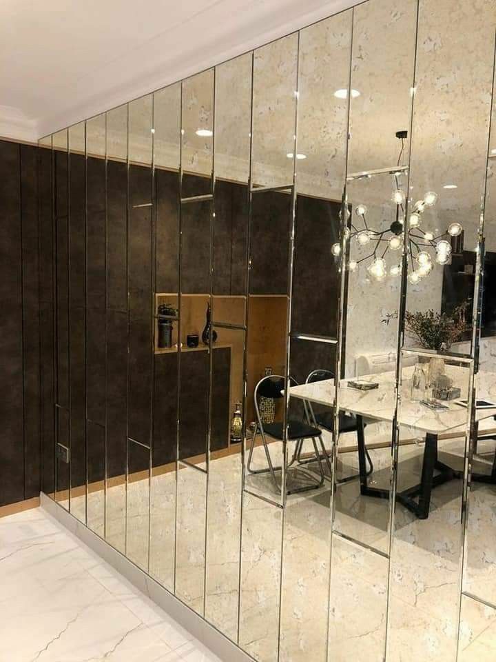 the reflection of a dining room table and chairs in a large mirror doored wall