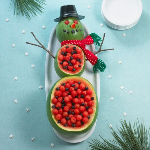 a snowman made out of watermelon is sitting on a plate with berries