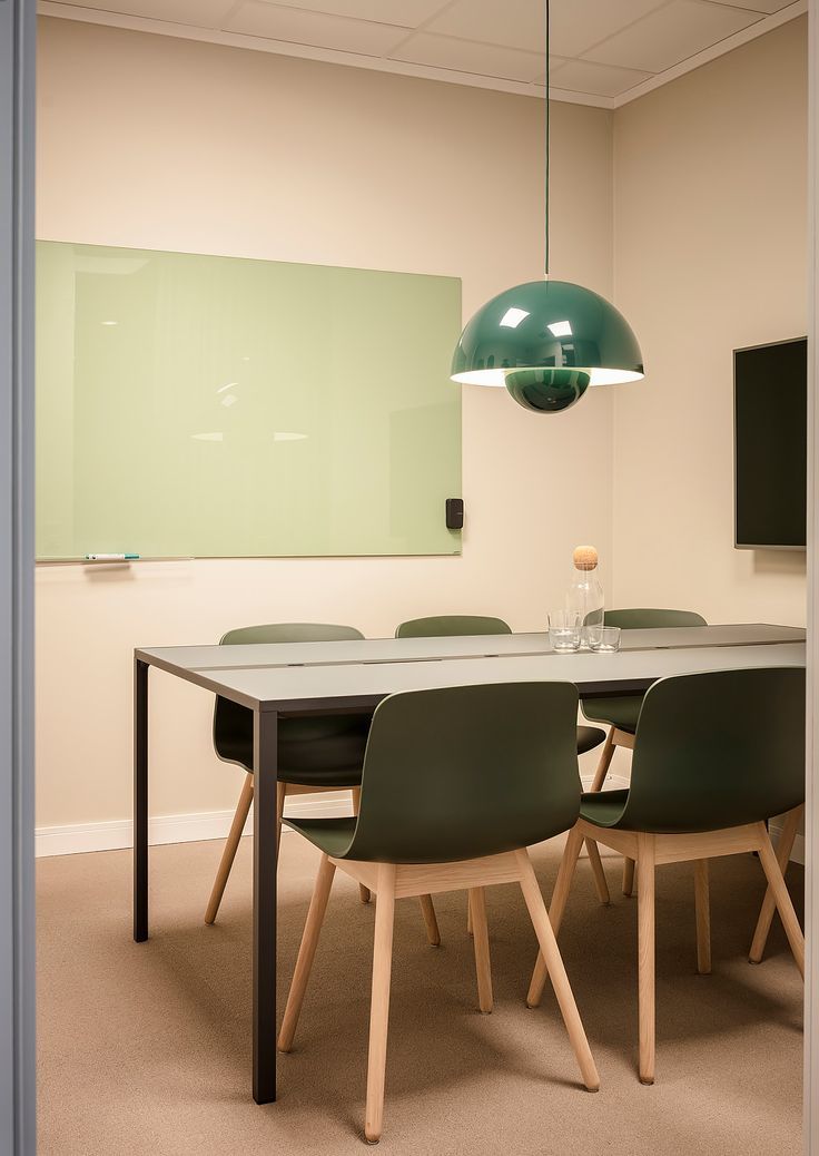 a room with a table, chairs and a green light hanging from the ceiling over it