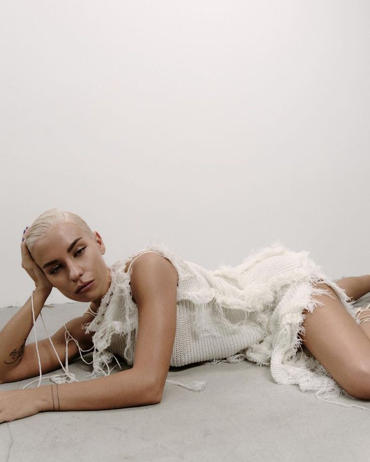 a woman laying on the floor with headphones in her ears and wearing a white dress