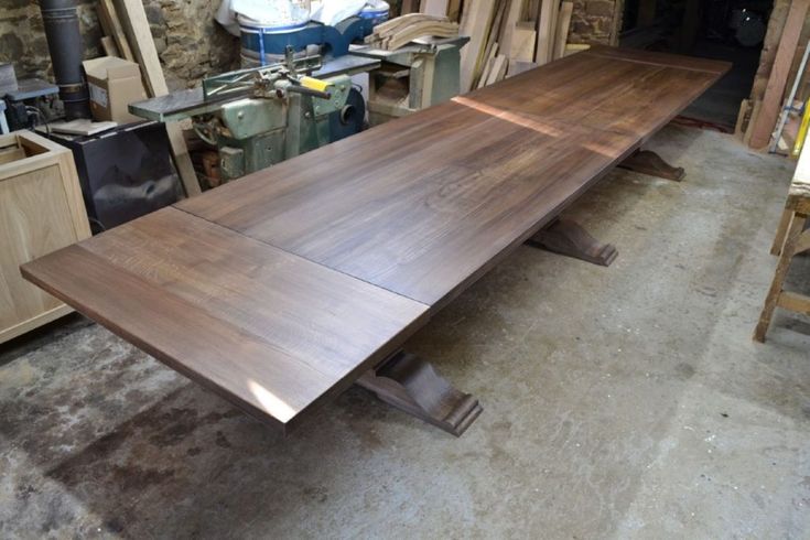 a large wooden table sitting inside of a room next to other woodworking tools and materials