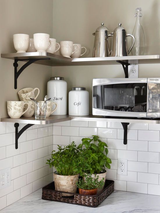 a kitchen shelf with coffee cups, mugs and plants on it in front of a microwave