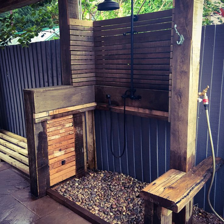 a wooden bench sitting next to a shower in a backyard area with wood slats on the walls