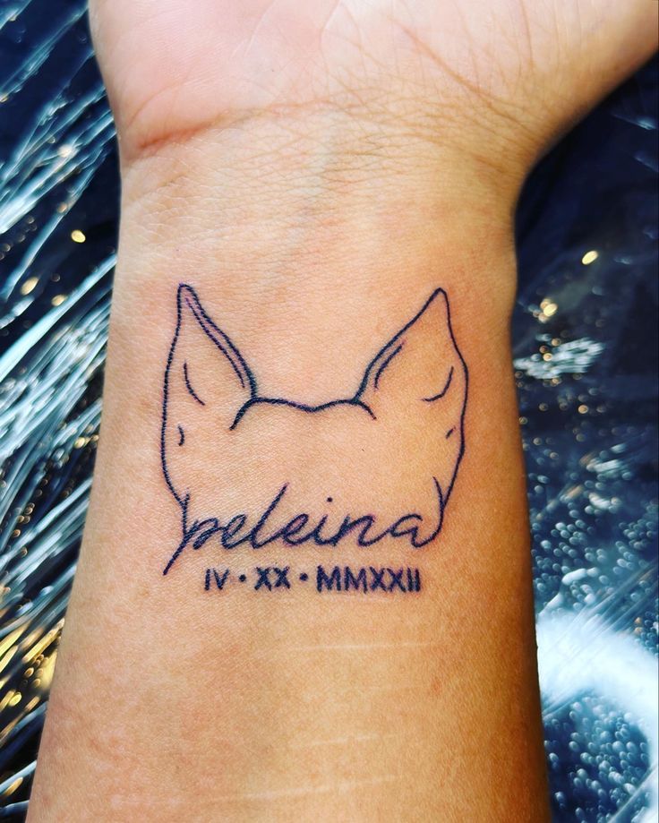 a small wrist tattoo with a dog's head and name written on the side