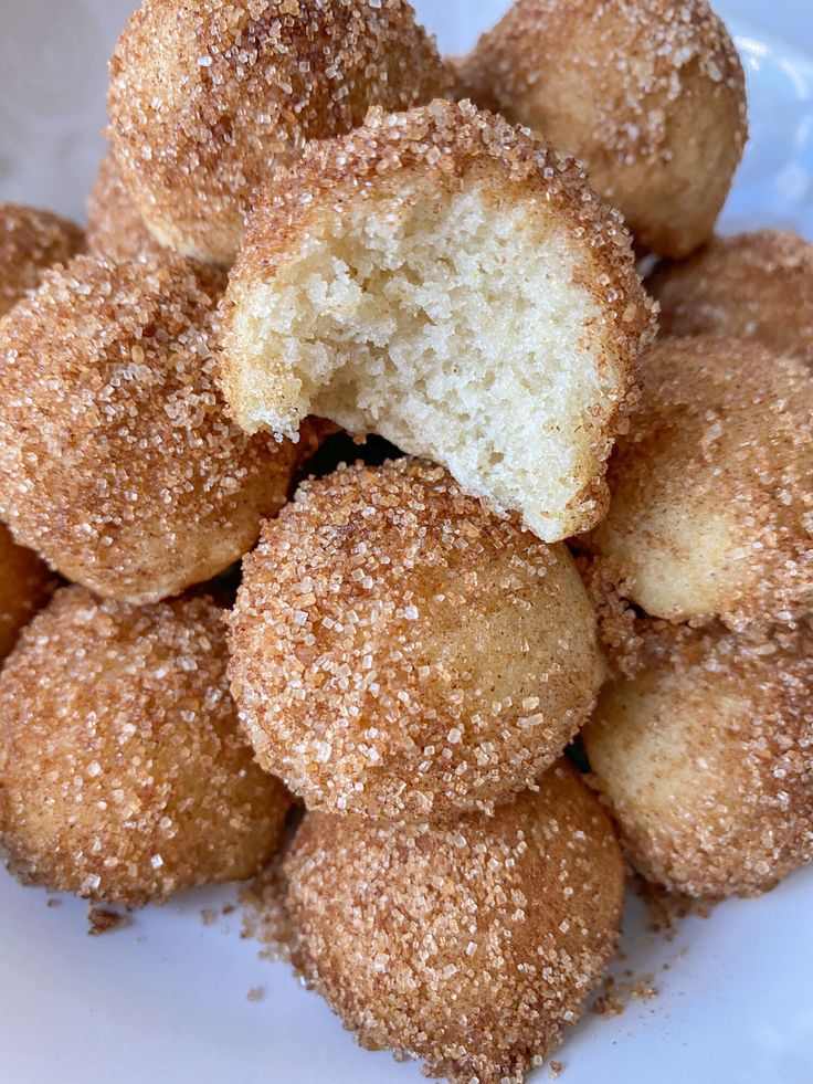 a pile of sugared donuts sitting on top of a white plate