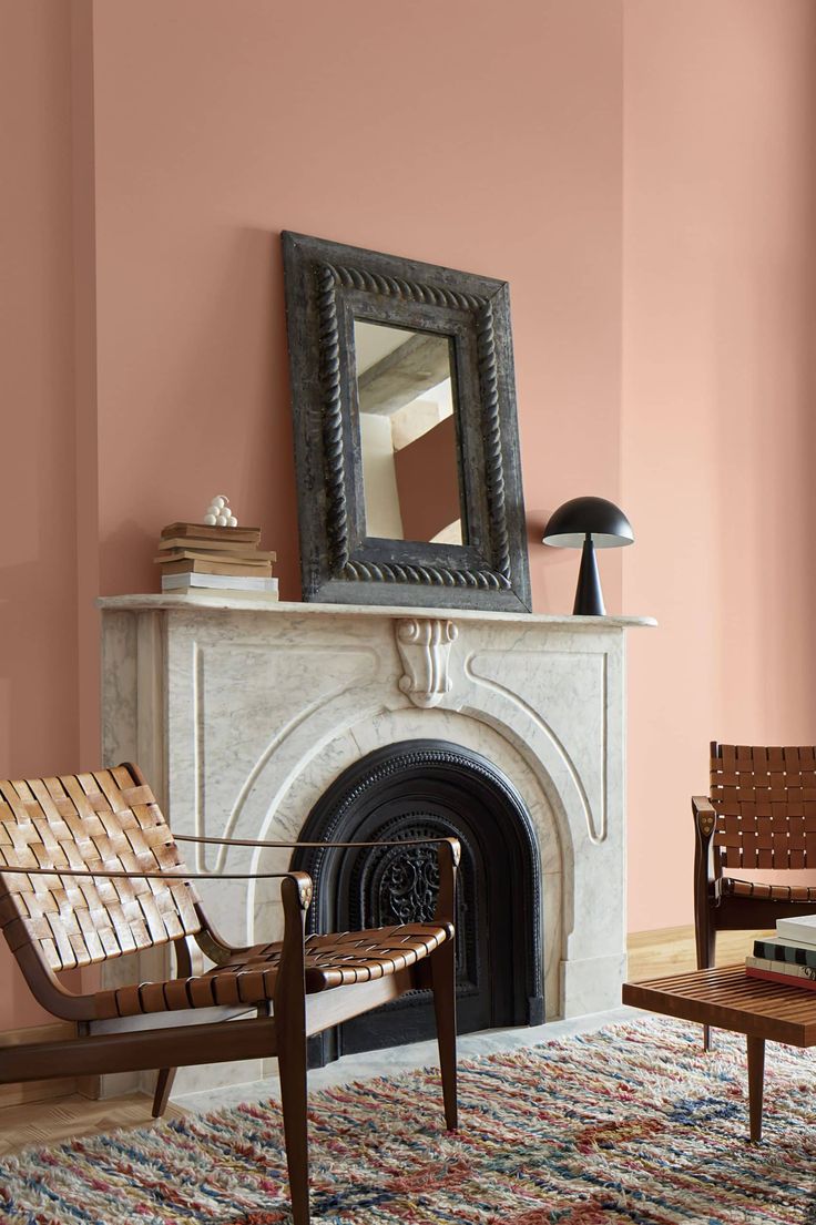 a living room filled with furniture and a fire place in front of a pink wall