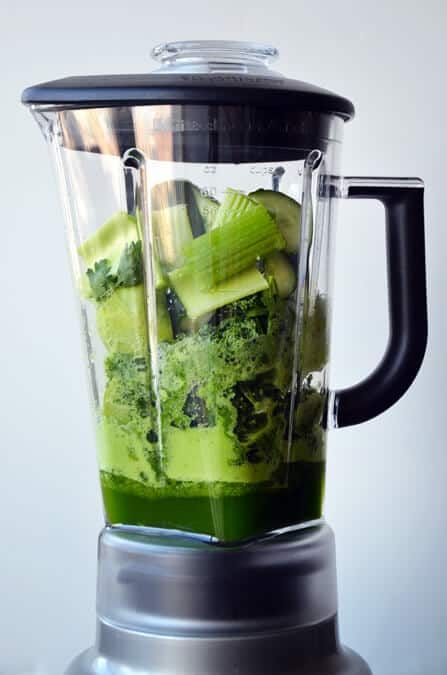 a blender filled with green liquid and vegetables