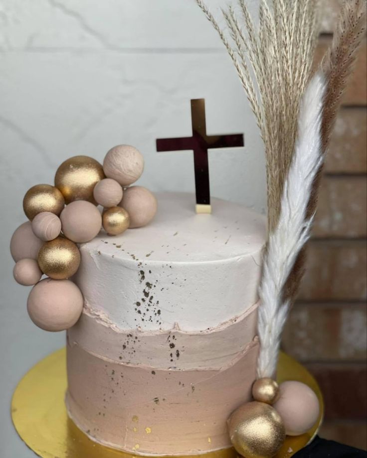 a white cake with gold decorations and a cross on top, sitting on a yellow plate