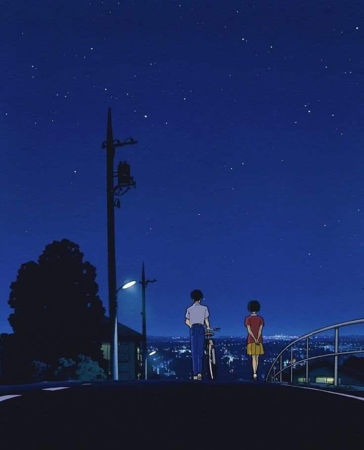 two people standing on top of a hill at night