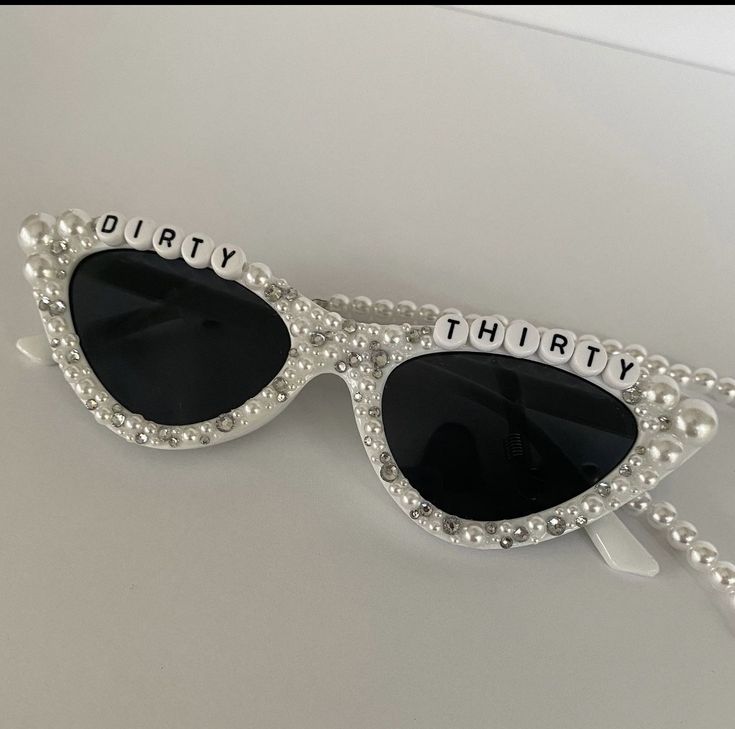 a pair of sunglasses with the words dirty thirty written on them and pearls attached to it