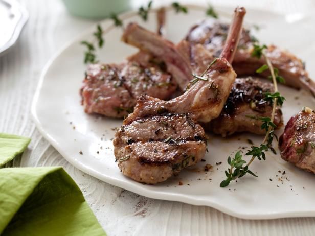 three pieces of meat on a white plate with herbs and seasoning around the edges