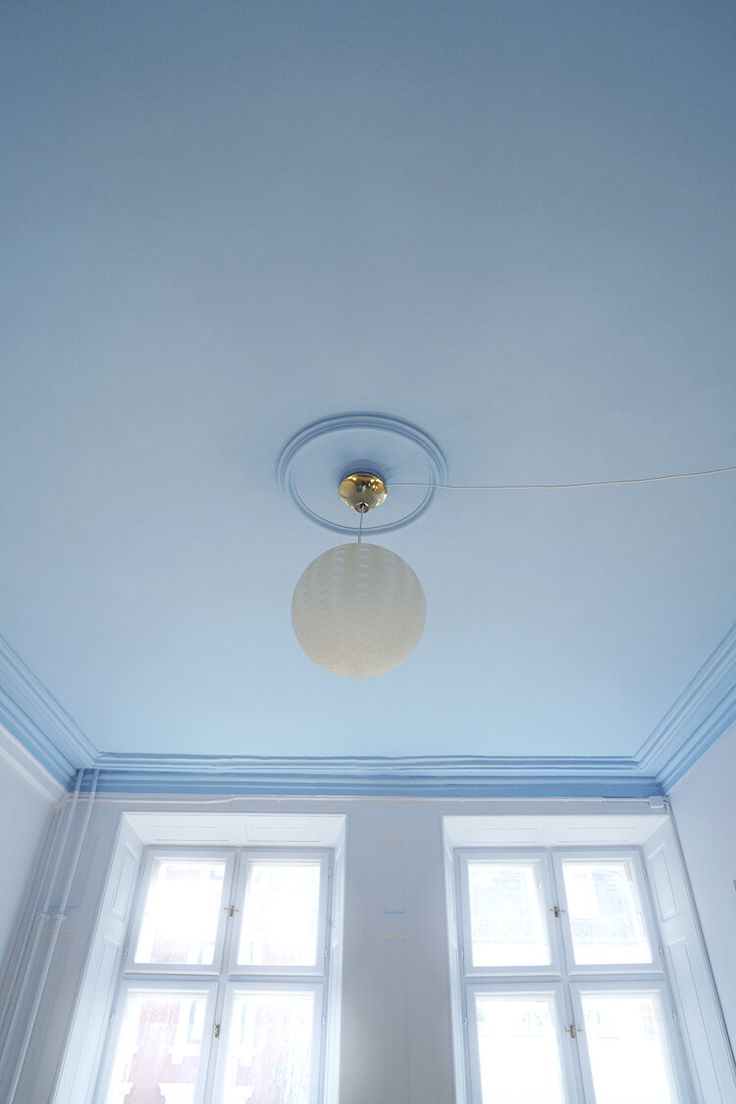 an empty room with two windows and a light fixture on the ceiling in front of them