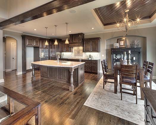 a large kitchen and dining room with wood flooring in the center, along with an island