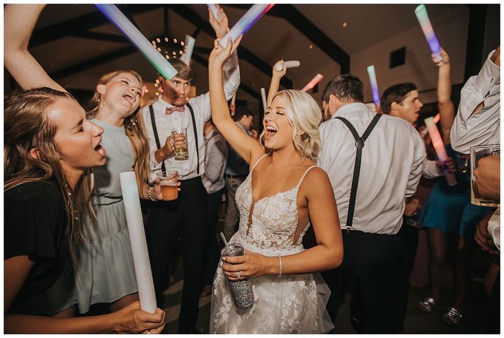 a group of people standing around each other at a party with their arms in the air