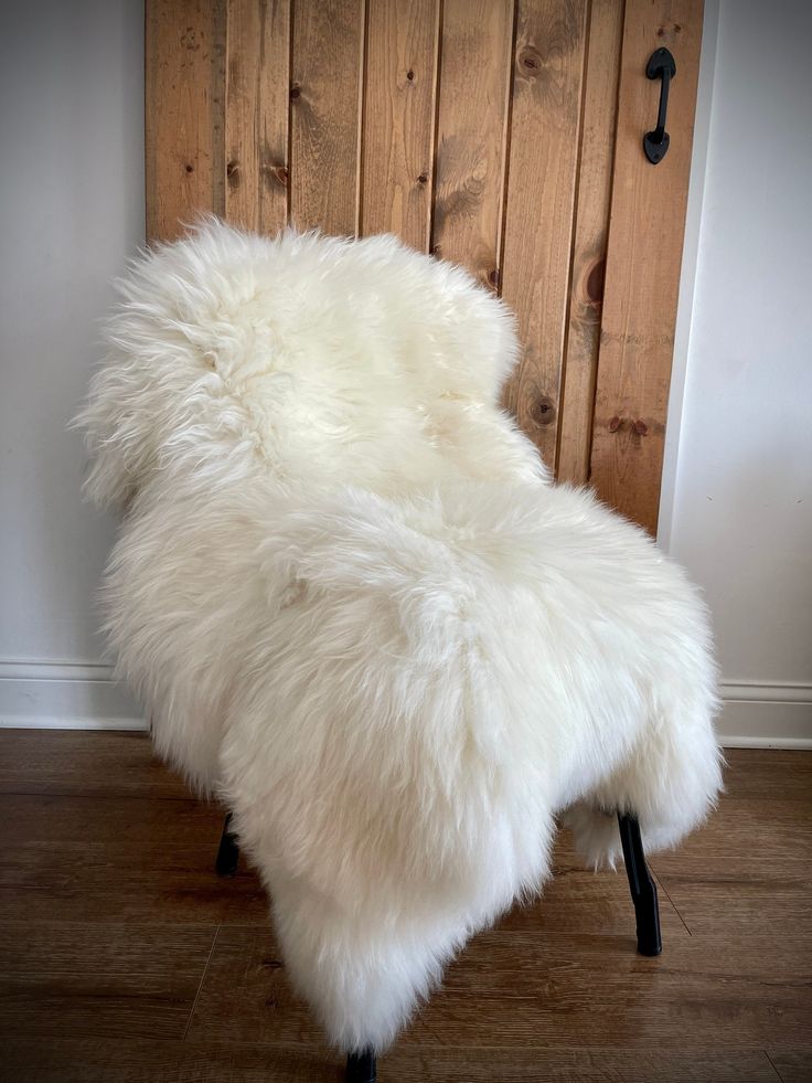 a white sheepskin chair sitting on top of a hard wood floor