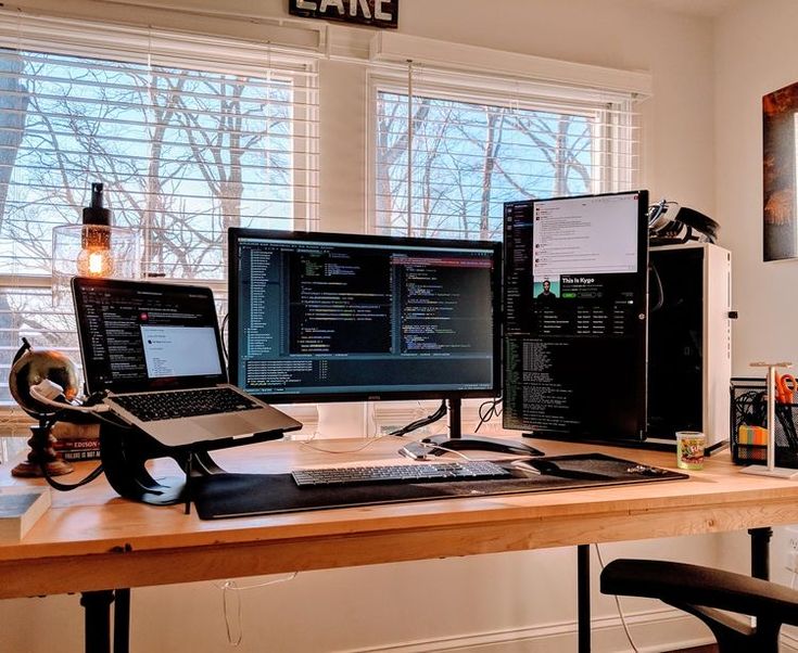 three computer monitors sitting on top of a wooden desk