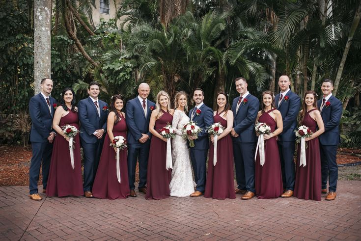 a group of people standing next to each other on a brick floored walkway in front of palm trees