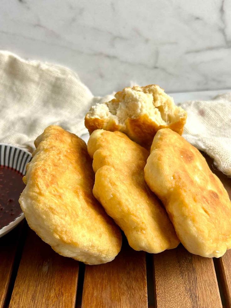 some fried food is sitting on a wooden table next to a bowl of dipping sauce