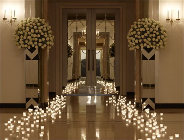 candles are arranged on the floor in front of an entrance to a building with columns and chandeliers