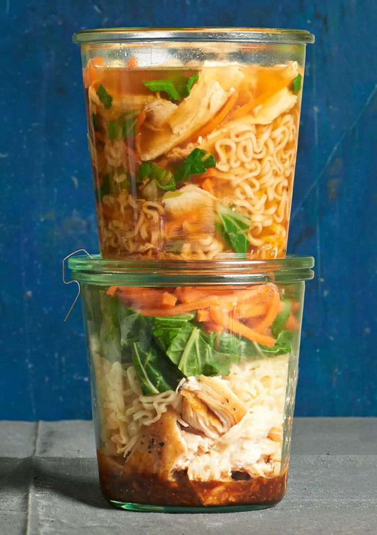 two glass containers filled with food sitting on top of a wooden table next to a blue wall