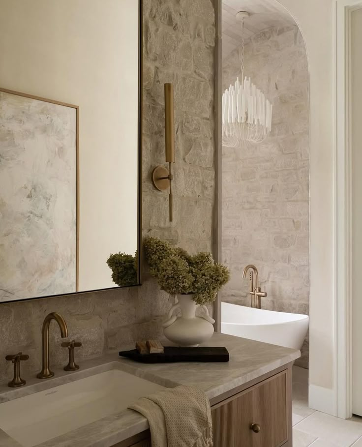 a bathroom with a sink, mirror and vase on the counter top in front of it