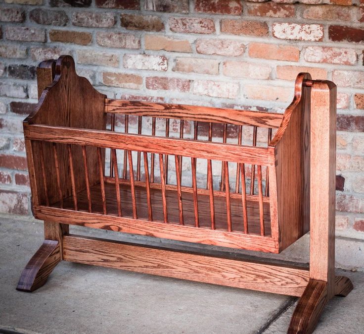 a wooden crib sitting on top of a cement floor next to a brick wall