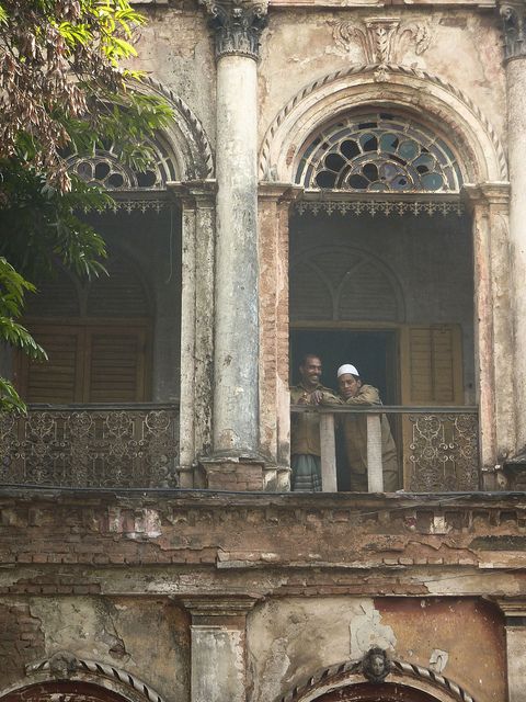 two men standing on the balcony of an old building