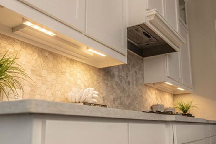 a kitchen with white cupboards and an island countertop, potted plant in the corner