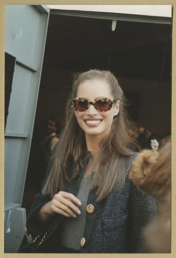 a woman wearing sunglasses standing in front of a door