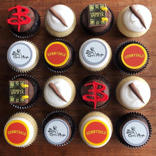 twelve cupcakes with various logos on them sitting on a wooden table next to each other