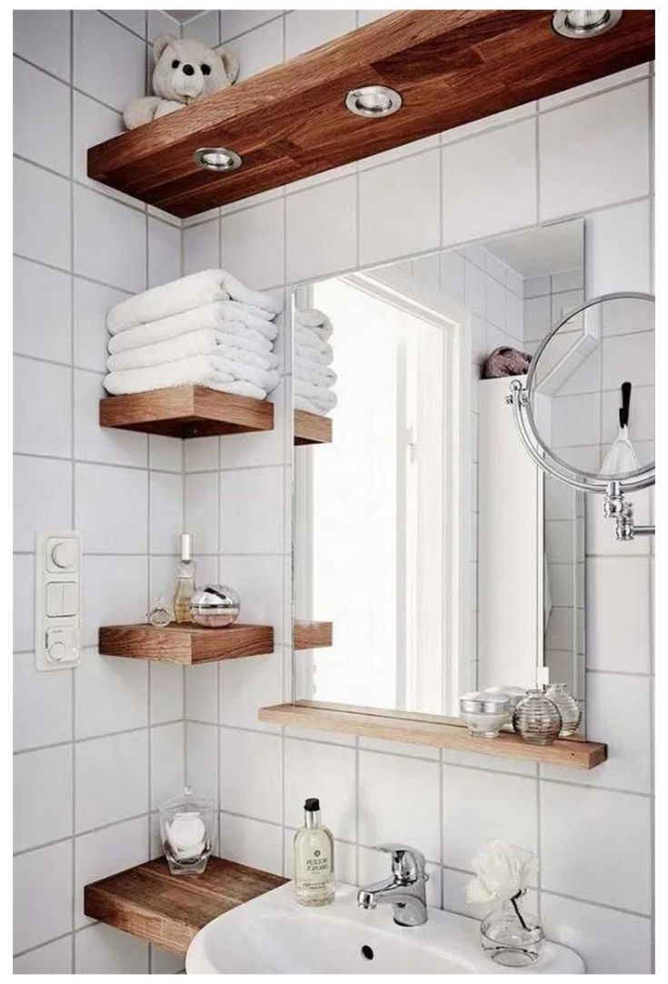 a bathroom with white tile and wooden shelves on the wall, along with a sink