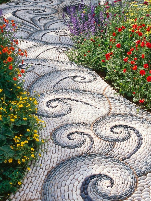 a garden path made out of cobblestones surrounded by flowers