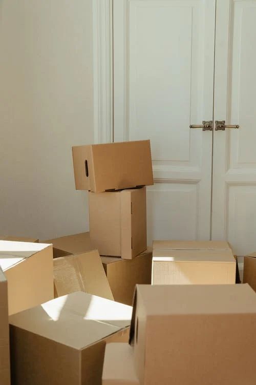 several cardboard boxes are stacked on the floor in front of a white door and closet