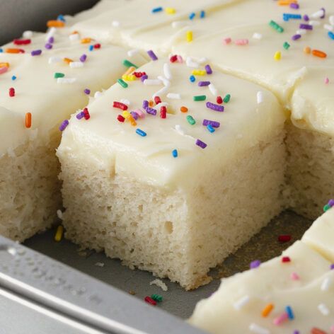 a cake with white frosting and sprinkles is cut into squares on a pan