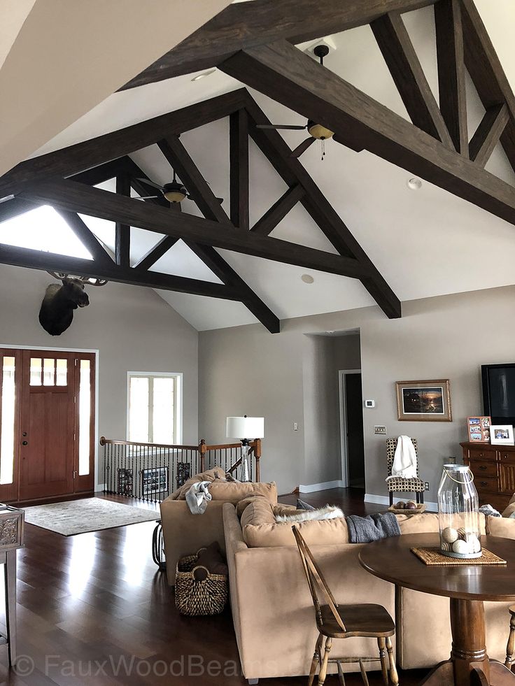 a living room filled with furniture and a wooden ceiling beam in the middle of it