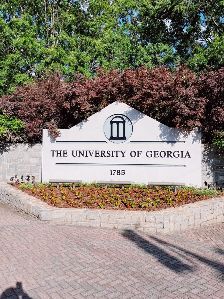 the sign for the university of georgia is shown in front of some trees and bushes