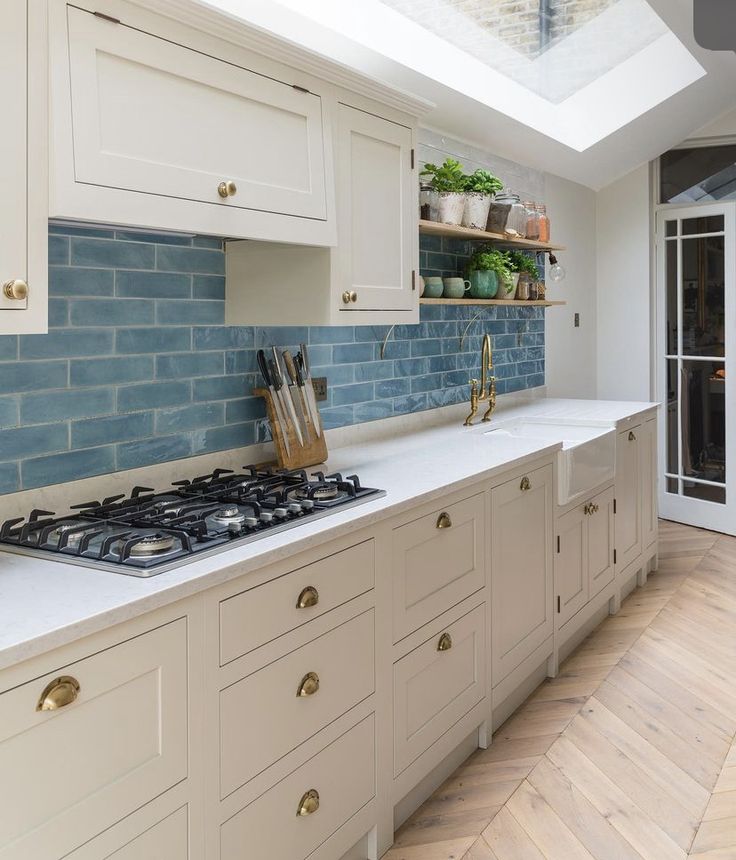 a kitchen with white cabinets and blue brick backsplash in the ceiling, along with wooden flooring