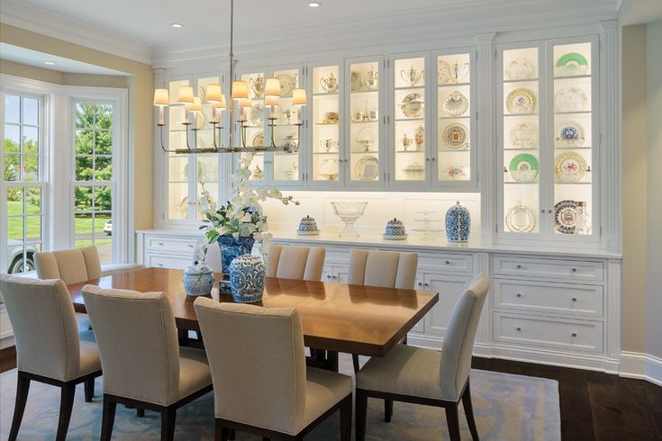 the dining room table is surrounded by chairs and china cabinet with glass doors on both sides